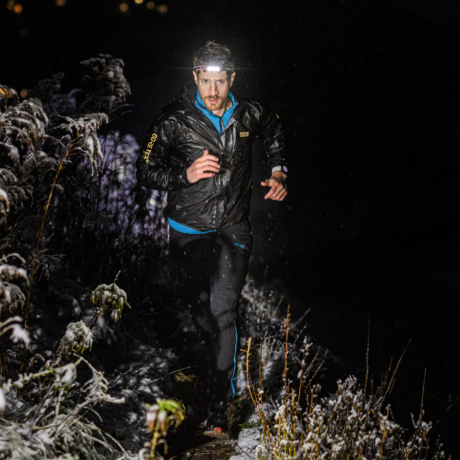 นักวิ่งเทรลใส่ไฟฉายคาดหัว Ledlenser วิ่งกลางคืนบนเส้นทางหิมะ (Trail runner with a Ledlenser headlamp on a snowy night trail)