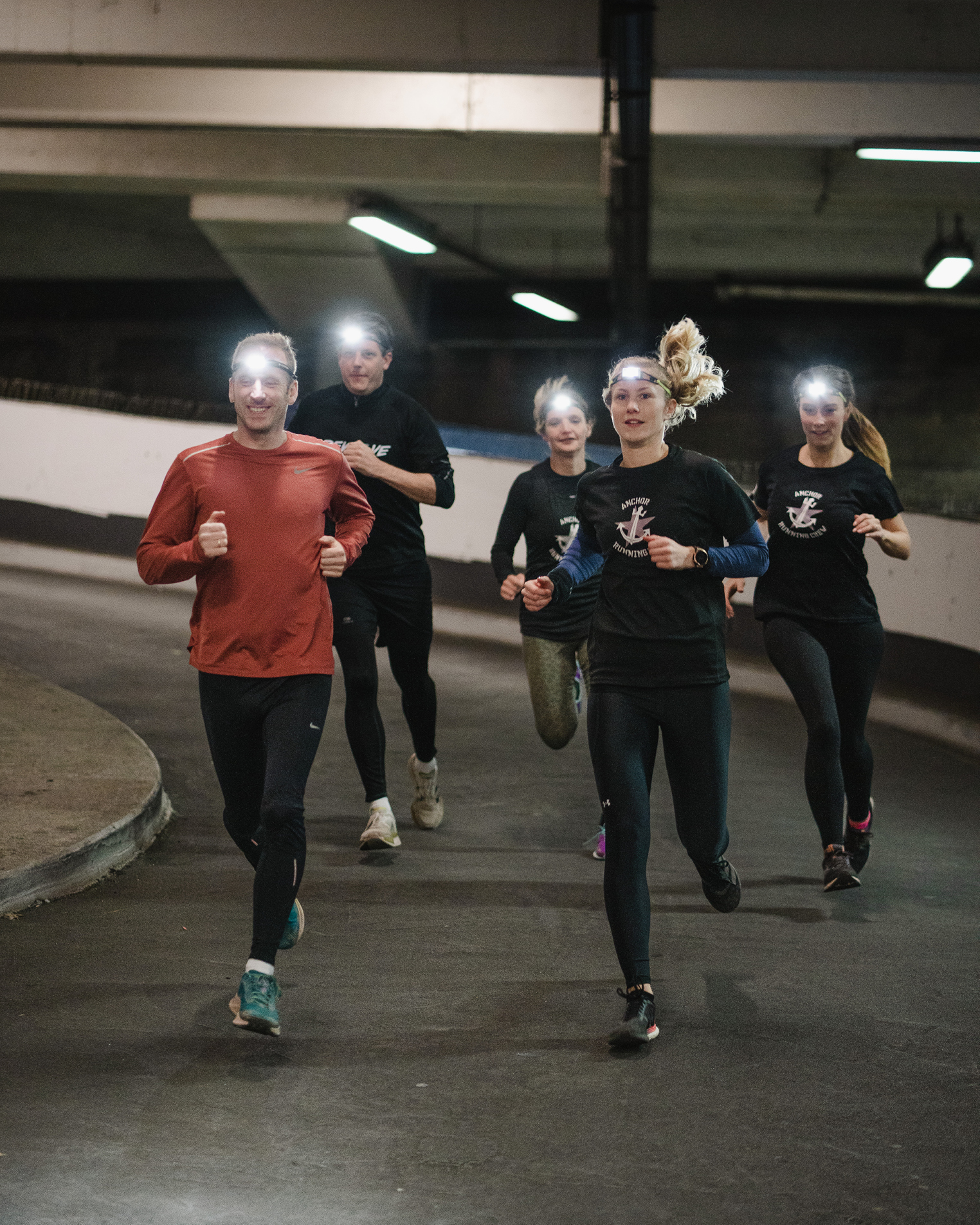 กลุ่มนักวิ่ง 5 คนสวมไฟฉายคาดหัว Ledlenser วิ่งกลางคืนในเมือง (Group of five runners wearing Ledlenser headlamps on a night run in the city)